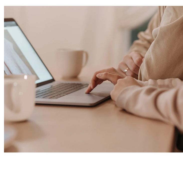 コーヒーを飲みながらパソコン画面を見る人